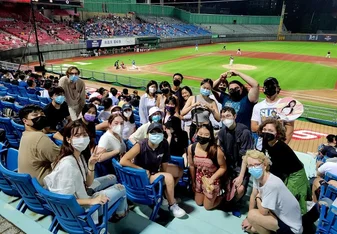 A large group of students posing for a picture at a baseball stadium at night